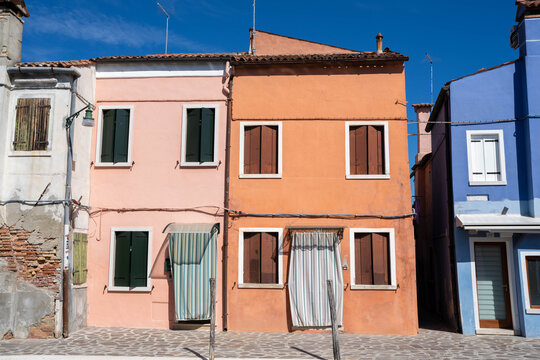 Two Colorful Homes in Burano Italy With Sheets Covering the Doorway