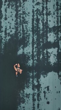 Aerial overhead view of female runner on a textured wet road