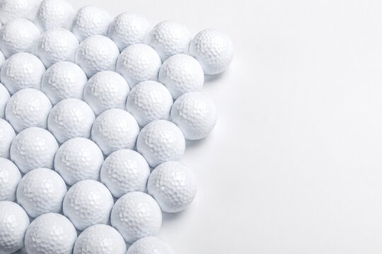Many white golf balls arranged in an organized pattern on a clean white background.