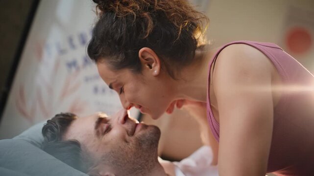 Close up couple flirting bed morning. Woman leaning over smiling boyfriend