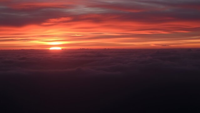 A vast landscape with a second wave of orange and pink sunset glow illuminating clouds.