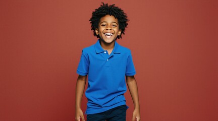 Obraz premium Happy young Black boy laughs in blue polo shirt on plain red background. Curly hair kid has joyful expression and is full of fun. Positive child face, energetic mood.