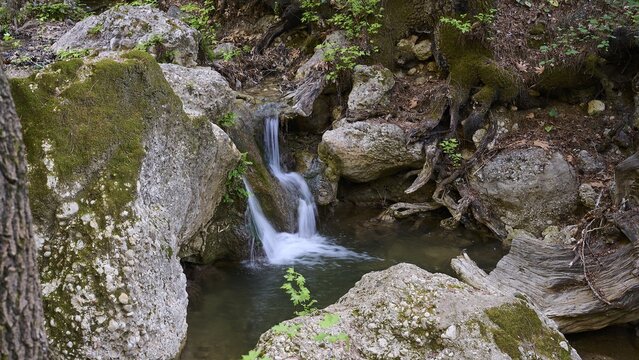 Small stream with waterfall, surrounded by moss-covered rocks, Butterfly Valley, Butterfly Valley, Rhodes, Dodecanese, Greek Islands, Greece
