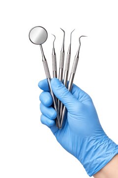 Dental tools held in gloved hand on white background.