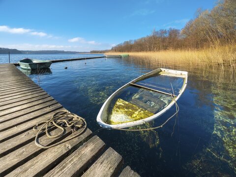 Sinking boat at Schaalsee, wooden jetty in the reeds with a rowing boat full of water, Schaalsee Biosphere Reserve, Mecklenburg-Western Pomerania, Germany