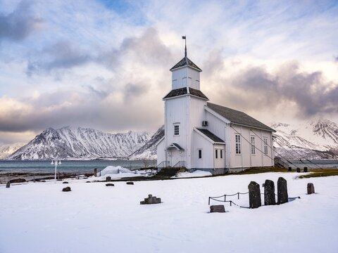Gims&oslash;y church with cemetery, snow-covered mountains in the background, winter, Gims&oslash;ya, Lofoten, Norway