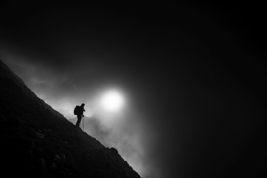 Mountaineer on mountain slope with fog against the light, Wildhaus, Appenzell, Switzerland