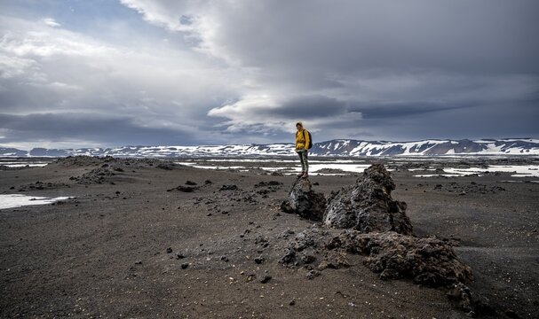 Hikers in snow-covered volcanic landscape with volcanic sand and petrified lava, crater of Askja volcano, Icelandic highlands, Iceland