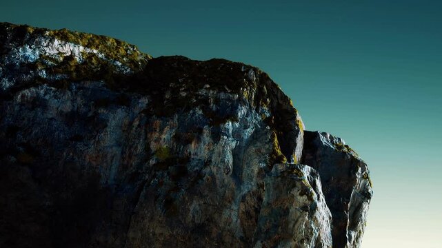 The scene shows a rocky cliff bathed in light against a dark sky. The cliff has rough textures and patches of greenery. It appears to be night time in a natural setting.
