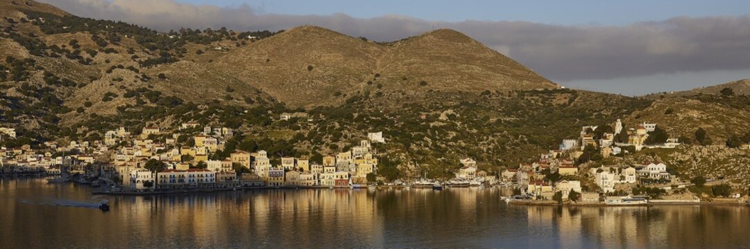 Picturesque coastal view with hilly landscape and calm waters under clear skies, Symi Town, Symi, Dodecanese, Greek Islands, Greece