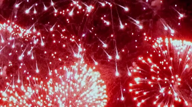 A brilliant display of red fireworks illuminates the dark sky over Saint Genevieve, Missouri. The bursts of light create a festive atmosphere.