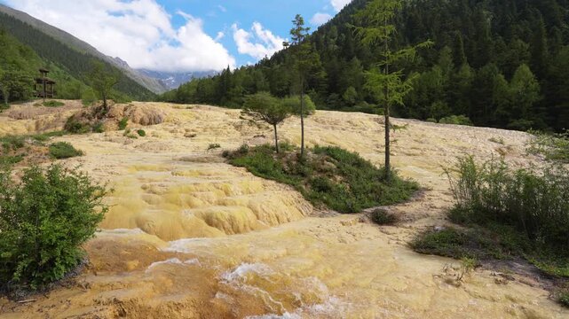 Yellow Travertine Pools with Waterfall Cascading Down under Blue Sky at Huanglong Scenic Area, Sichuan, China