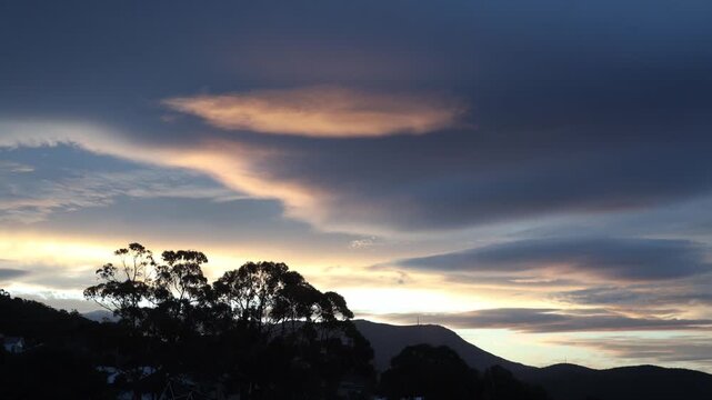 timelapse of golden sunrise clouds over tasmanian mountains into moody dusk