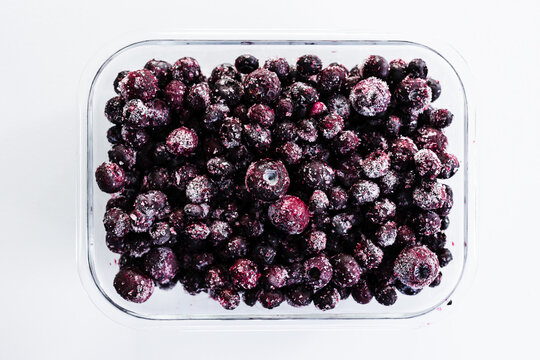 close up of frozen blueberries with ice crystals in glass container
