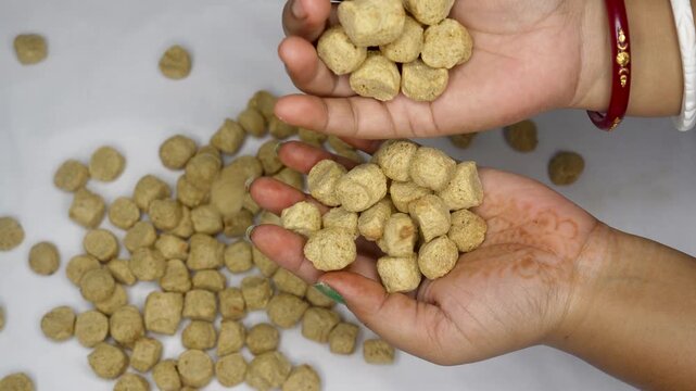 Close up of woman hand holding a handful of raw dry soya chunks over a white background. plant based protein rich food. healthy food concept.