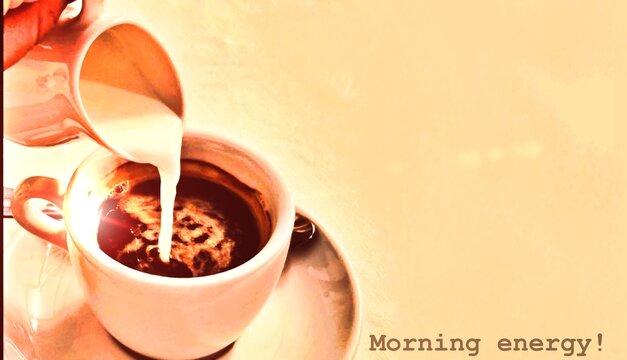 Latte art being poured into white ceramic cup. Warm morning coffee concept.