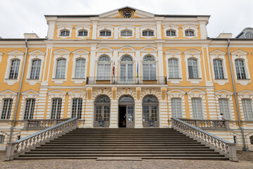 Fototapeta premium Grand Yellow Baroque Palace Facade With Symmetrical Staircase And Ornate Windows