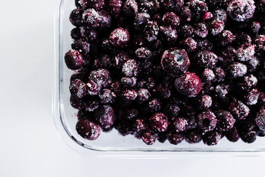 close up of frozen blueberries with ice crystals in glass container