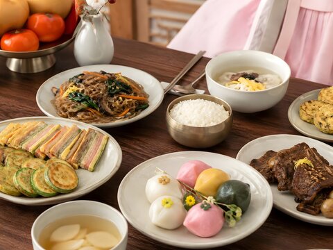 Korean holiday food table with hanbok and traditional dishes