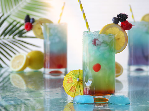 Colorful icy summer tropical cocktail drinks with fresh citrus fruits cocktail garnish on glass surface for summer drinks concept.