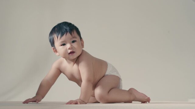 4K Happy adorable infant wearing diaper crawling forward with cheerful smile.