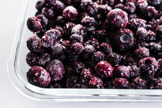close up of frozen blueberries with ice crystals in glass container