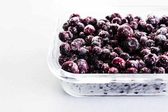 close up of frozen blueberries with ice crystals in glass container