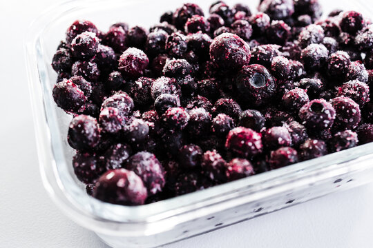 close up of frozen blueberries with ice crystals in glass container