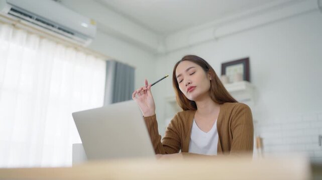 Beautiful young Asian woman working with laptop computer in home kitchen. Work at home