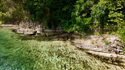 Tropical limestone shoreline with crystal clear coastal water. Sunlit cliffs and transparent sea create a pristine tropical landscape perfect for travel, tourism and nature themes. © Houston