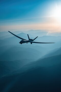 Dramatic shot looking upward at a military drone flying over mountains during sunset with sunlight illuminating the scene
