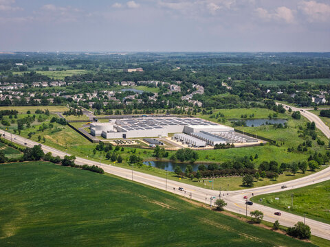Aerial view of a modern data center facility with solar panels on the roof, cooling units and server buildings