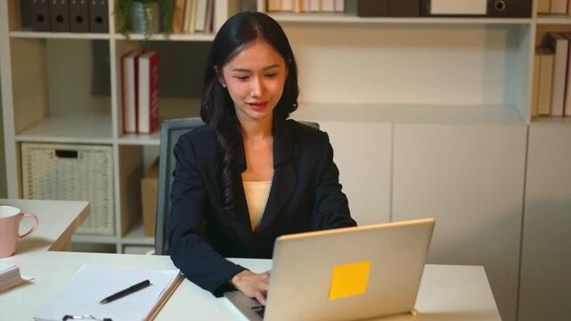 Young Businesswoman Using AI Chat Bot Laptop at Office Desk with Data Dashboard in Background