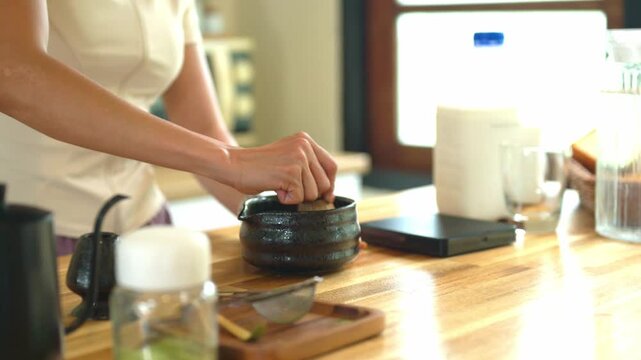 Closeup Whisking Matcha Green Tea in Traditional Black Bowl on Wooden Kitchen Counter