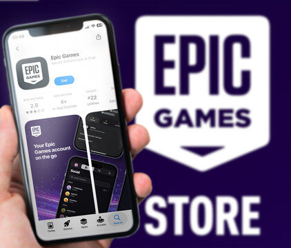 Epic Games App Store Listing Displayed on Smartphone Held Against Blurred Epic Games Store Logo and Wordmark Background