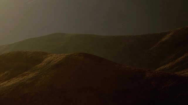 Light falls on the slopes of hills in a mountainous region during sunset. The scene shows natural forms in soft colors and shadows. The hills create a simple and clear view.