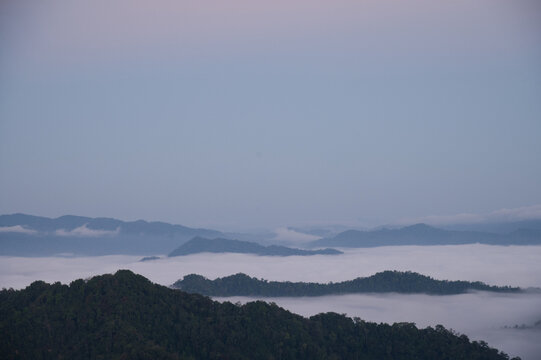 Breathtaking aerial view of misty valleys and lush green tropical rainforest mountains at dawn