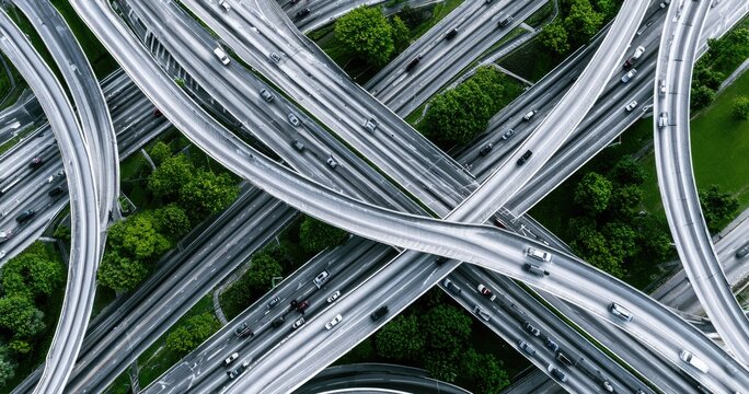Intricate highway interchange from above, weaving through lush green trees