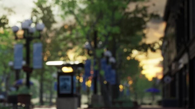 The scene shows a city park with tall trees and streetlights. The sun is setting, and the sky is colorful. People may be walking or sitting on benches enjoying the view.