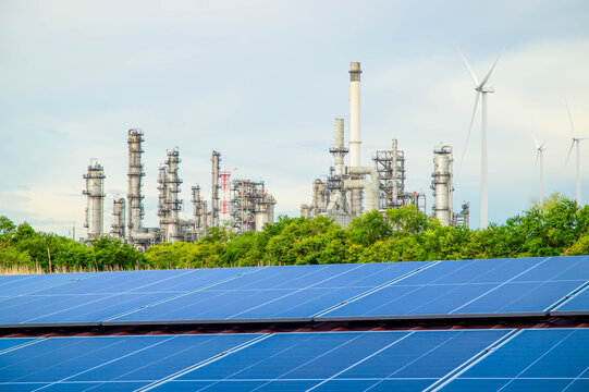 Solar panels with petrochemical oil refinery factory in background. Clean energy and sustainable development concept.Energy transition concept. 