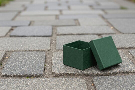 Small green gift box with lid on paved stone path