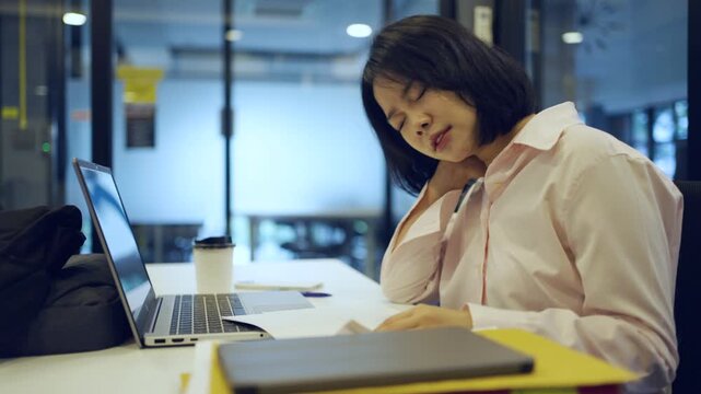 Young Asian woman working at office and have a pain office syndrome