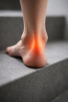 Anatomical illustration of human foot and ankle showing bones, muscles, and highlighted area indicating pain or injury in the ankle region against a gradient background