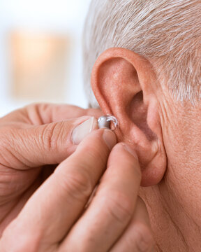 Hearing aid senior ear caregiver hands elderly person hearing assistance close up