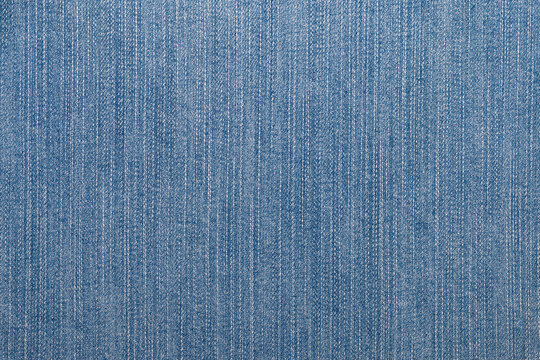 Close-up of blue denim jeans fabric texture with visible woven threads and textile details