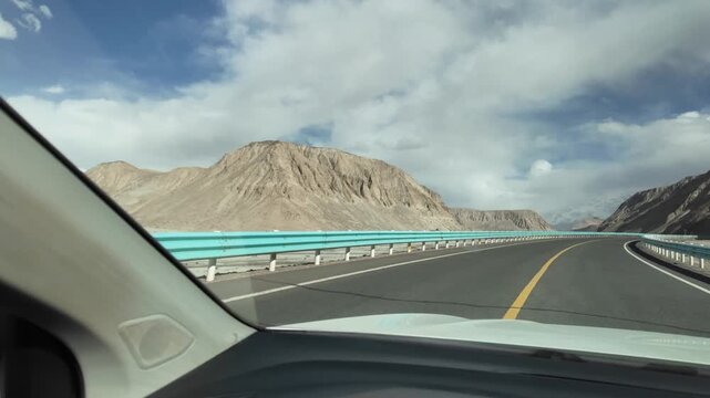 Car view driving along smooth modern G314 highway towards snow mountains near Karakul Lake Xinjiang