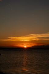 Obraz premium Sunset Over Water With Mountain Silhouette