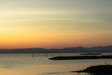 Obraz premium Sunset Over Calm Lake with Distant Mountains