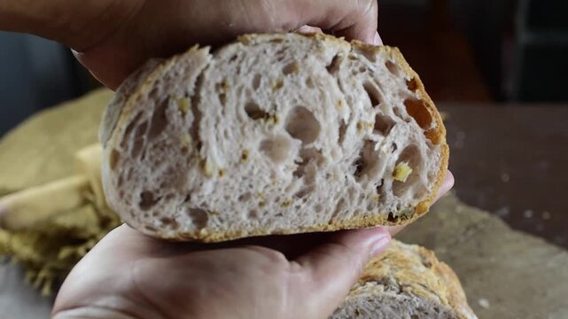 Close up of baker checking the softness of a sliced artisan sourdough bread loaf, showing beautiful internal crumb structure and crispy golden crust. Perfect for healthy food and traditional baking.