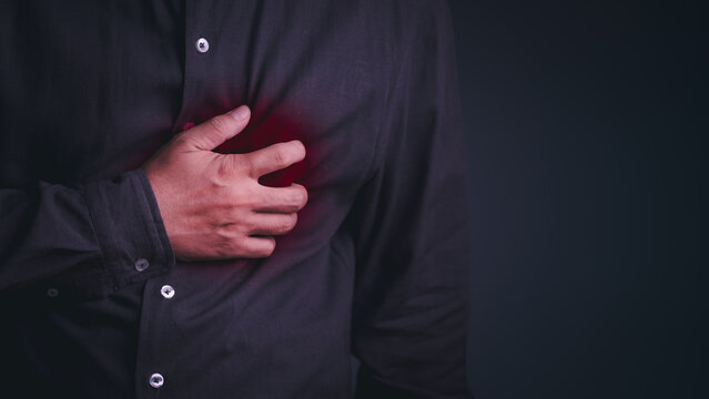 A grown man clutches his chest in agony during a severe heart attack, illustrating a critical cardiovascular and medical emergency.